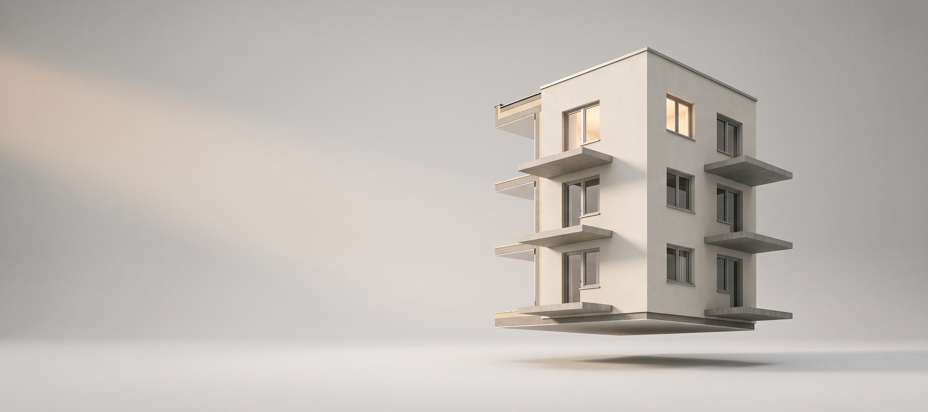 L'angle d'un immeuble d'habitation découpé et suspendu dans la lumière : trois étages, des dalles de balcon qui traversent la façade, l'isolant visible sur la tranche et deux fenêtres allumées.